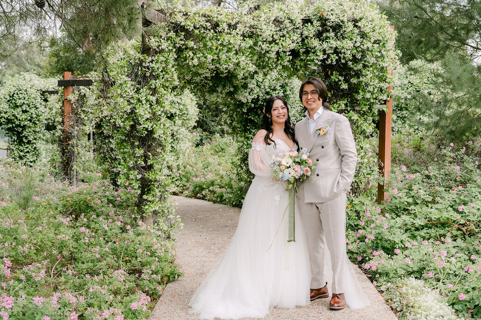Bride and groom holding hands on the garden path at Ethereal Gardens