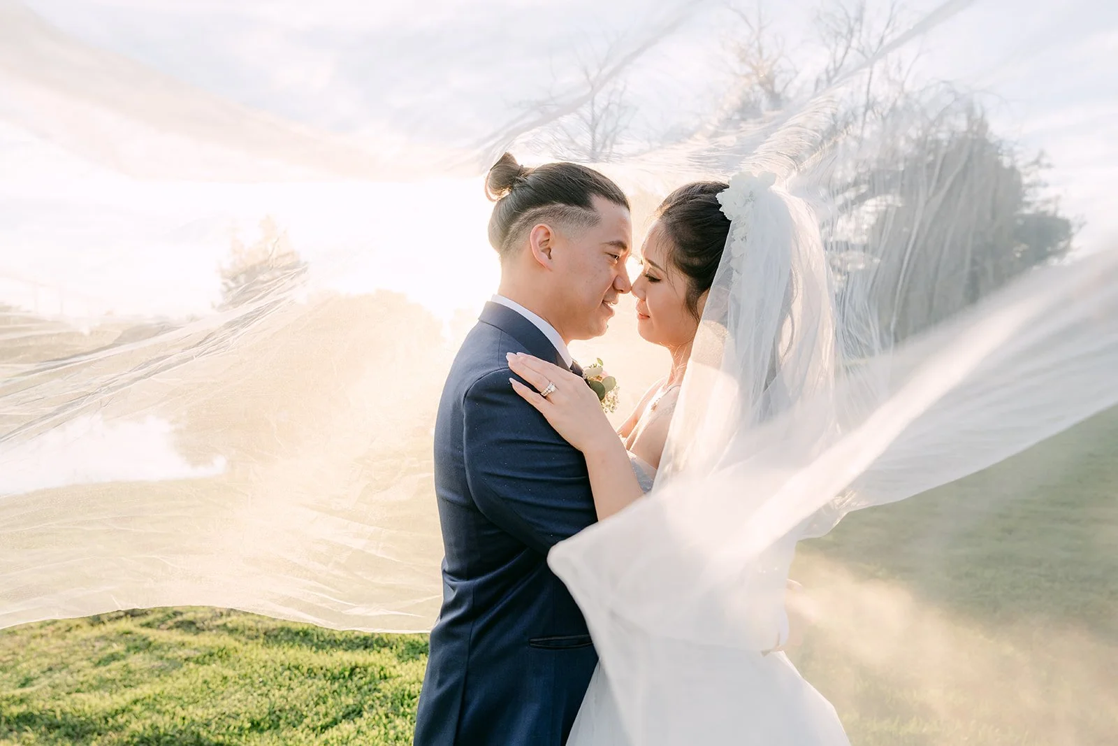 Kate and Michael kissing under the veil on the golf course.