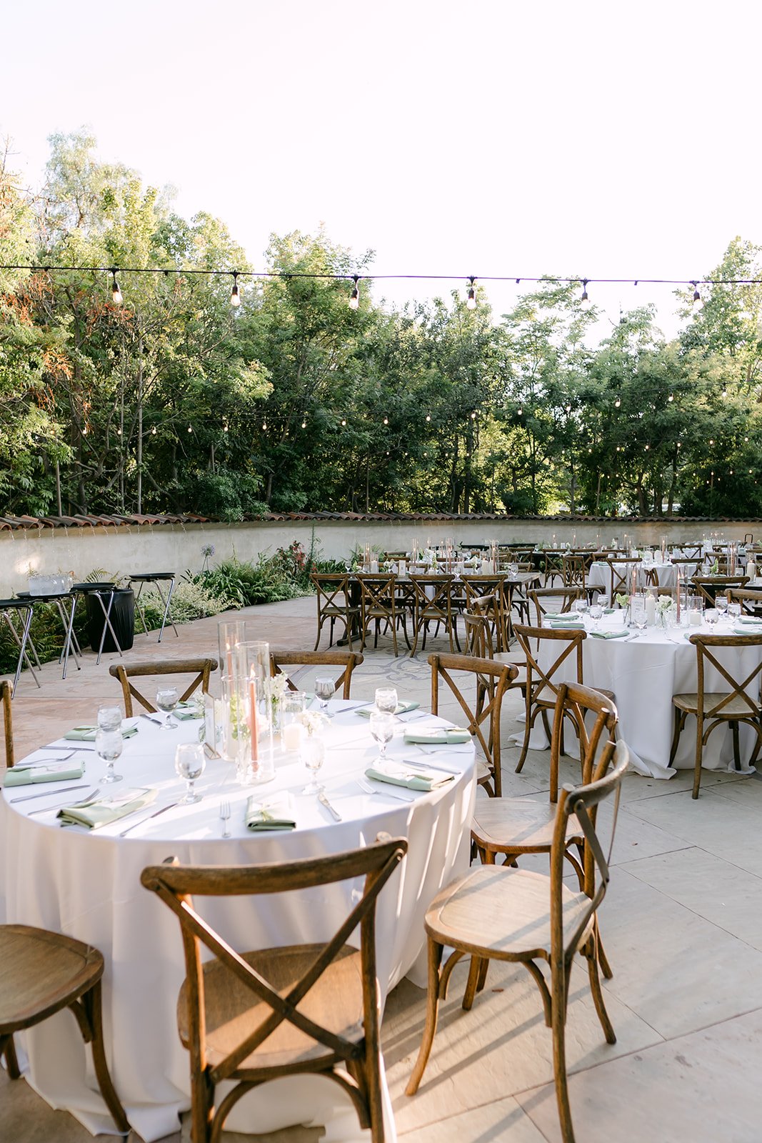 Round reception tables with white linens on the patio at Eden Gardens.
