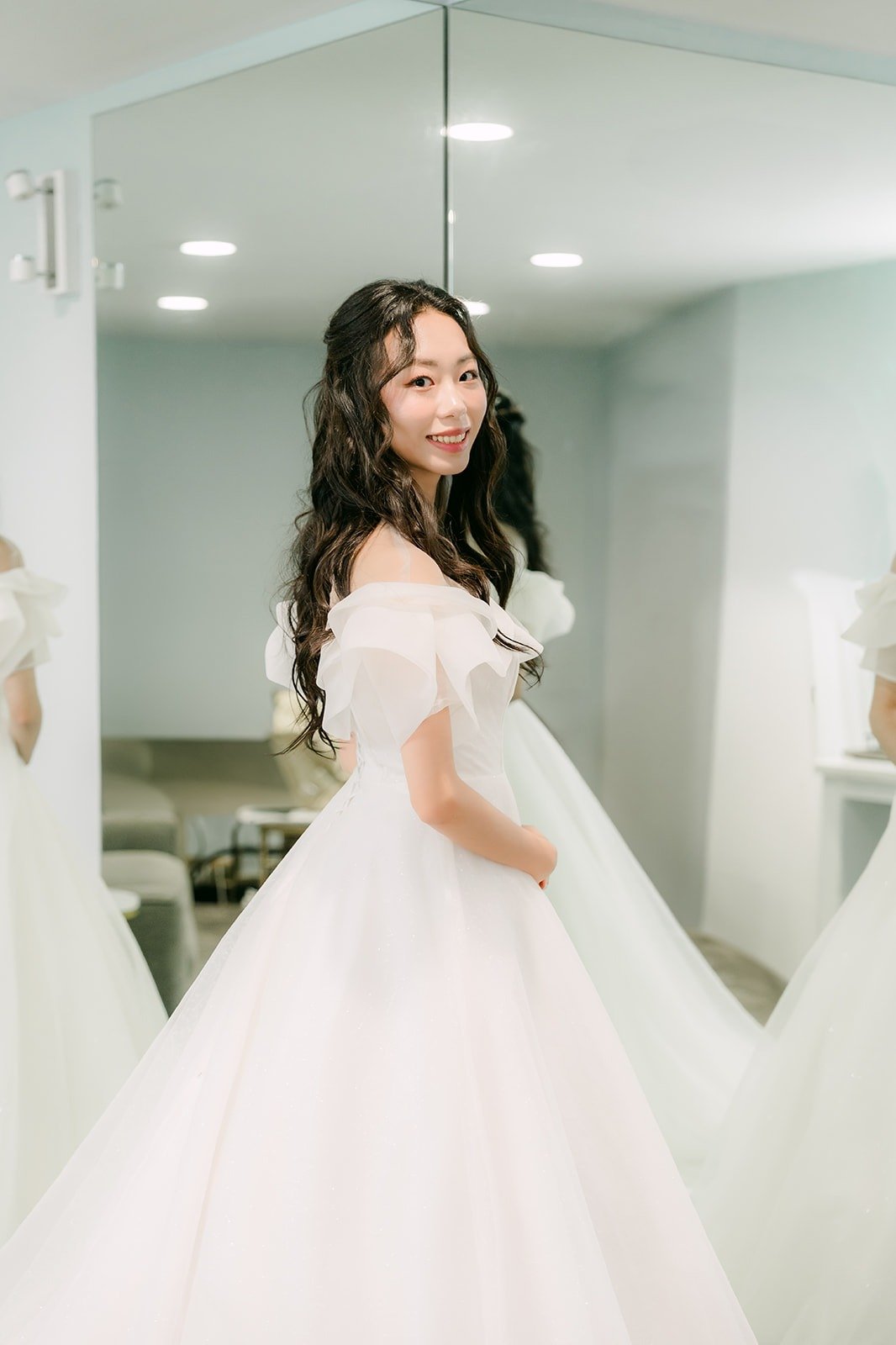 Jeannie smiling in her gown beside the bridal suite mirror