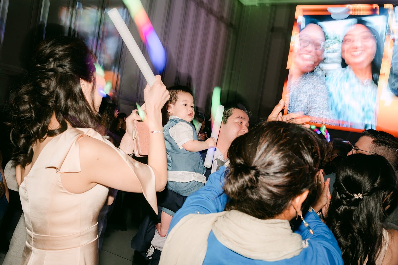 Guests waving glow sticks on the dance floor in front of the big screen