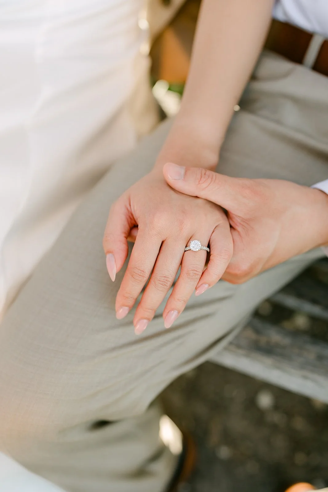 Kim's hand and engagement ring resting on Vincent's knee.