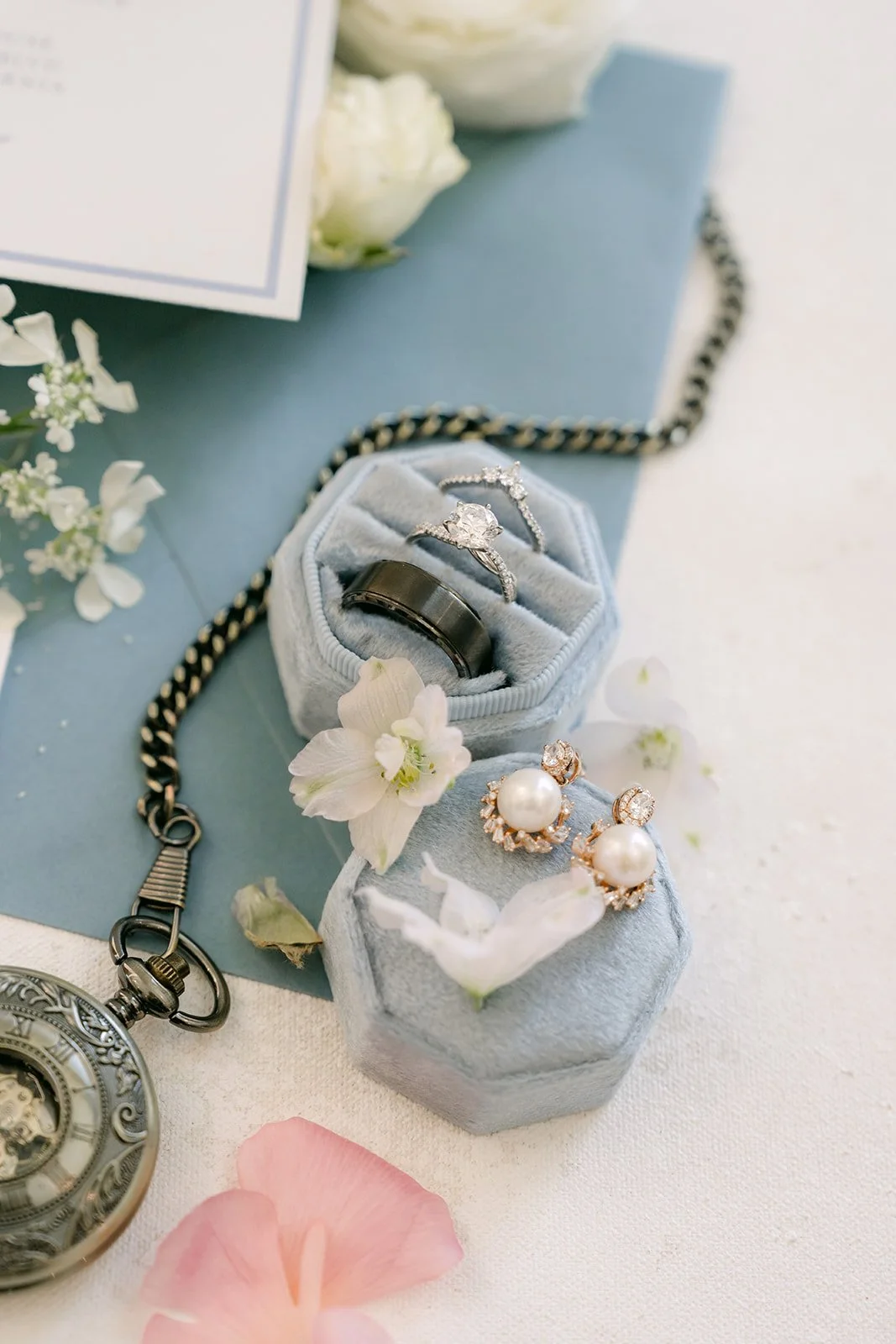 Wedding rings in a velvet ring box with a vintage pocket watch