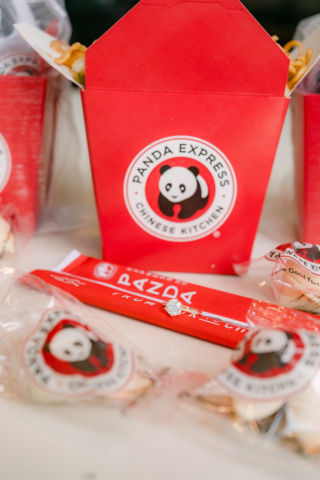 A Panda Express takeout box with chopsticks and fortune cookies on the table.