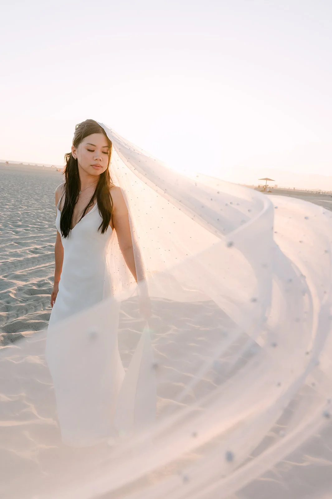Justine twirling her veil on the sand