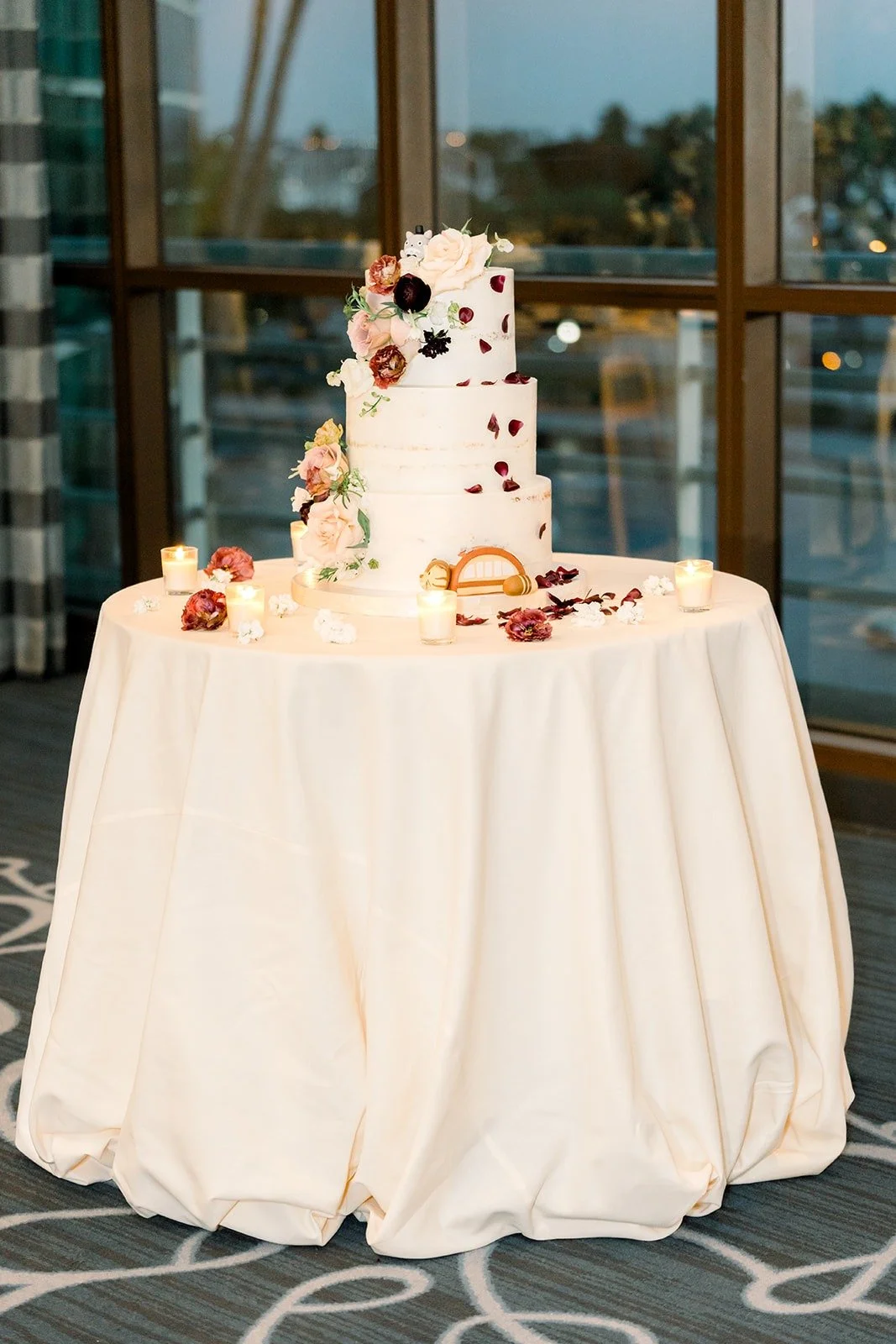 The white tiered wedding cake by the ballroom windows