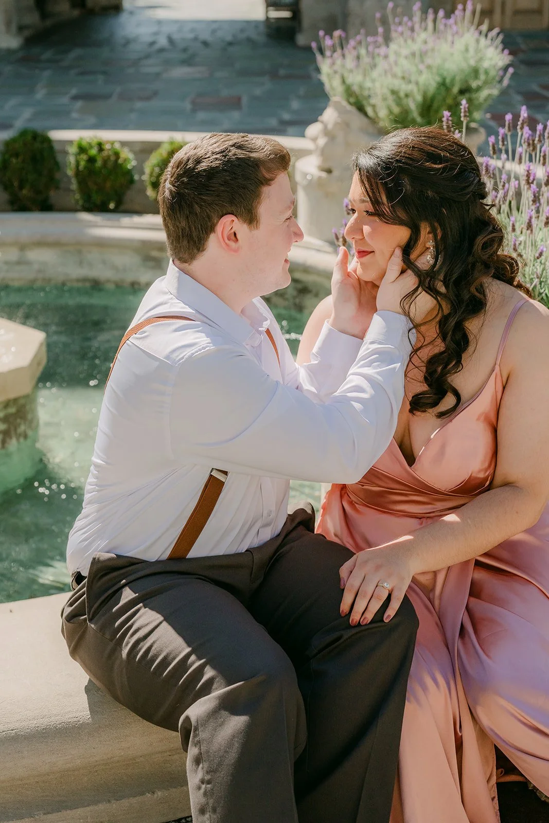 Saira touches Matthew's face as they sit by the fountain.