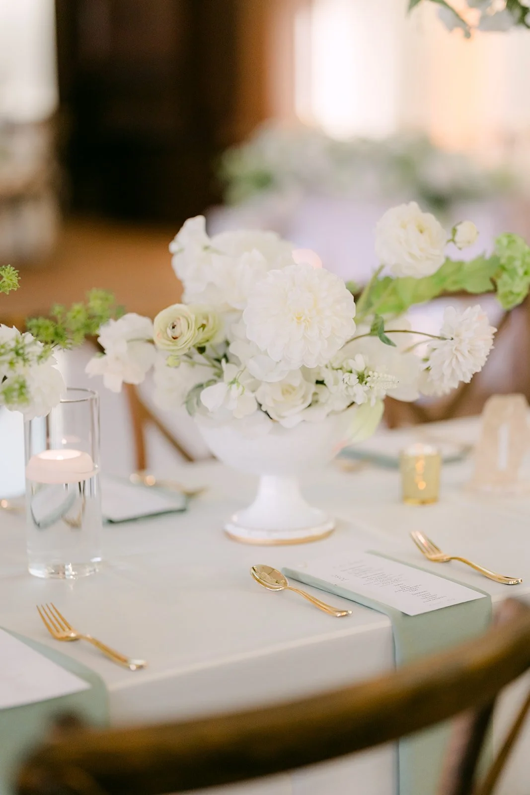 A white floral centerpiece on a reception table.