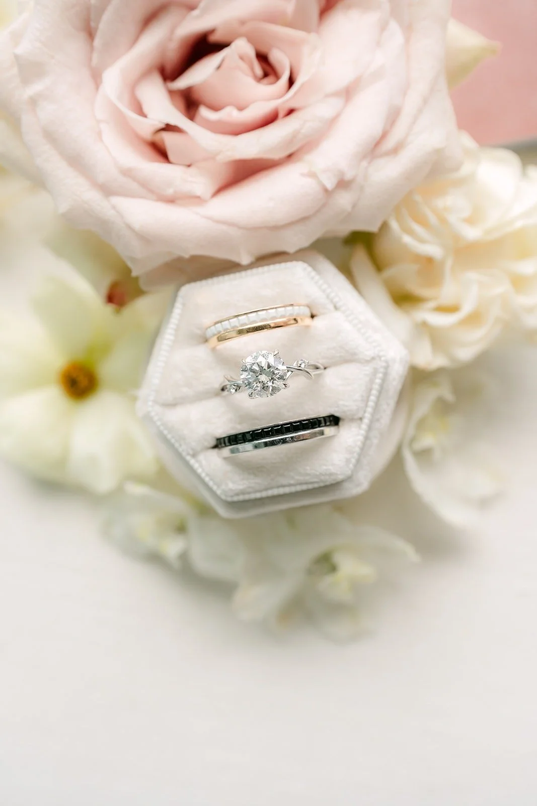 Angela's engagement ring in a white hexagon ring box among blush roses