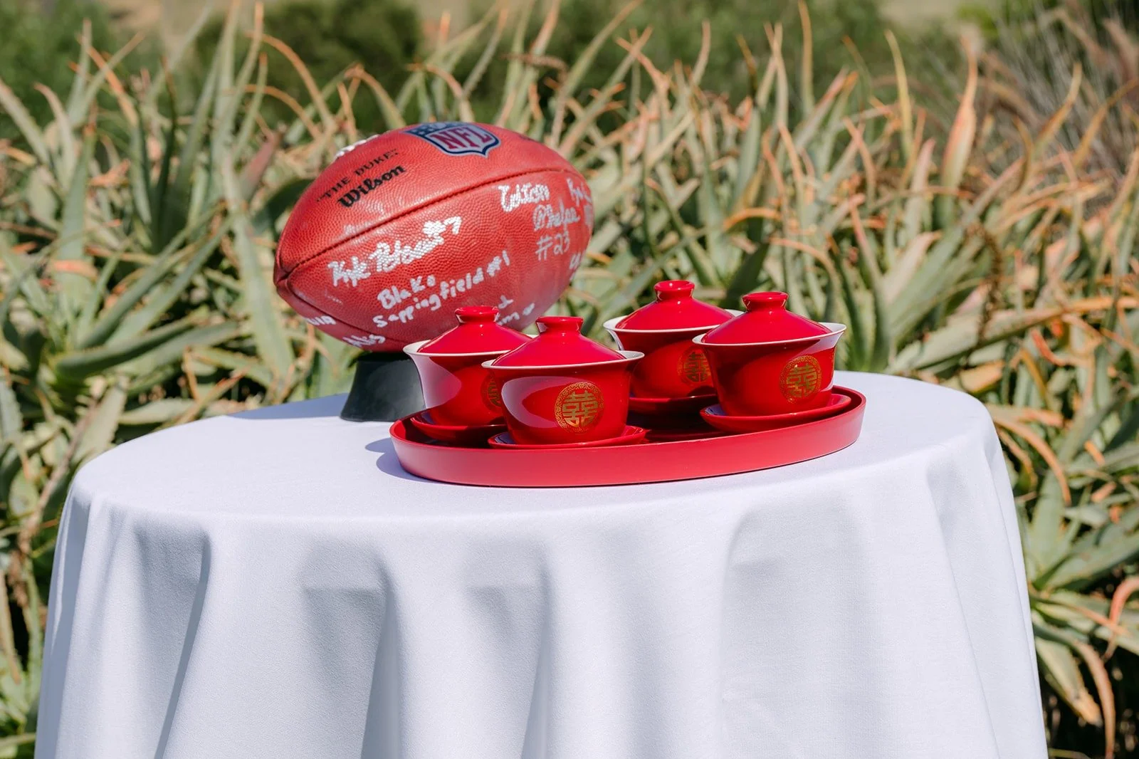 A football and a red tea set waiting on a small white table at the ceremony
