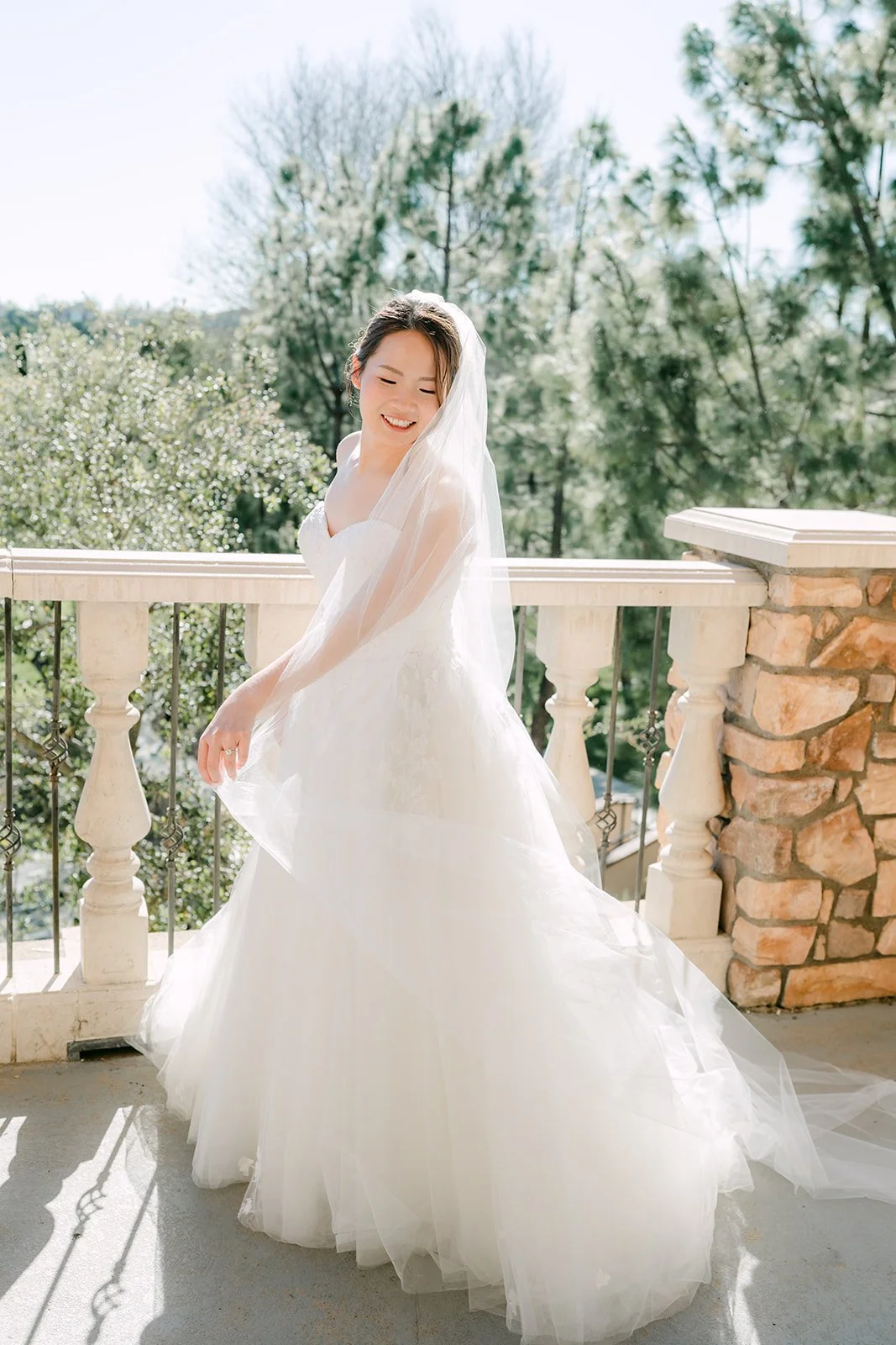 Bride twirling her gown and long veil on the balcony