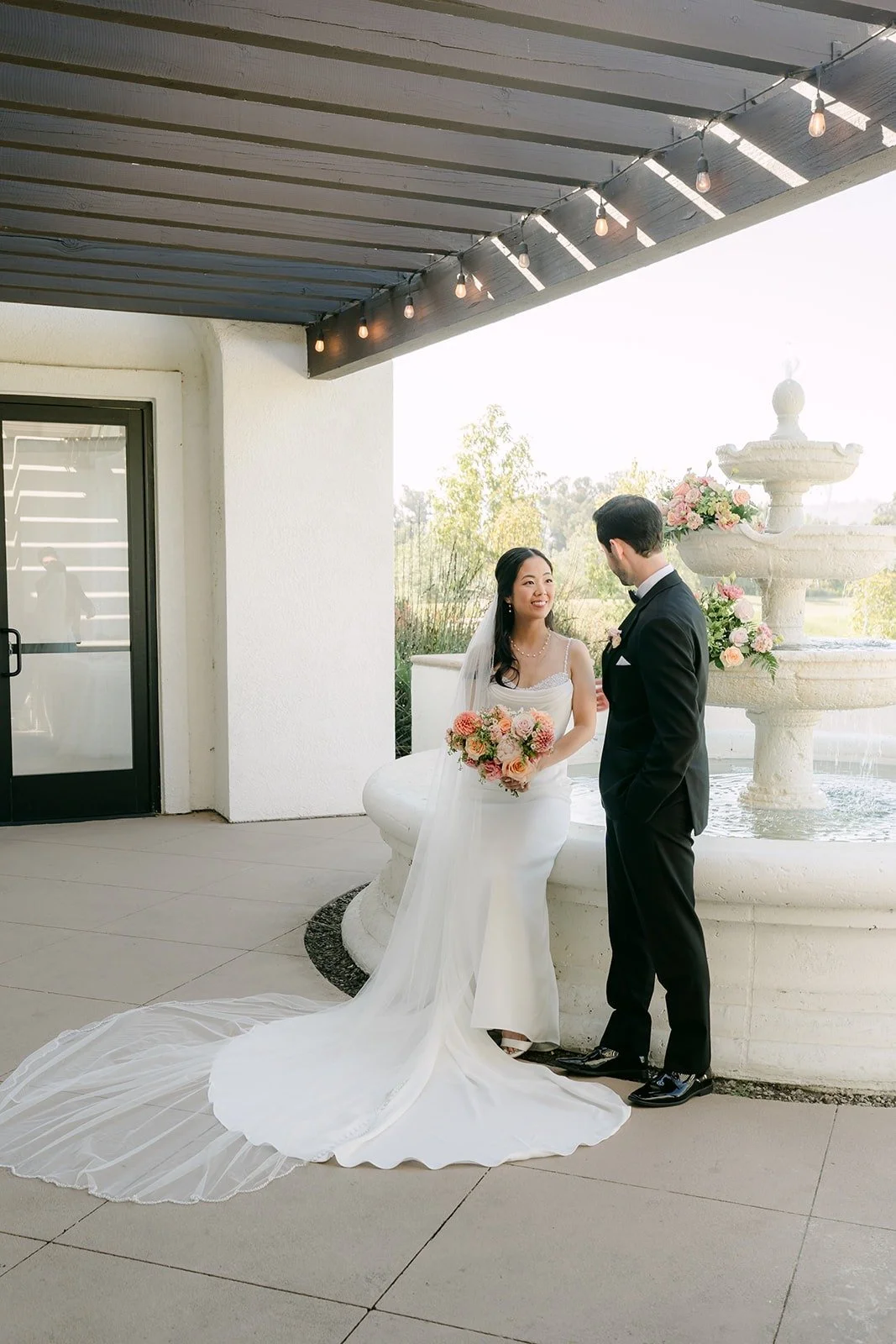 Stephanie and Kevin under the covered patio with her train spread across the floor