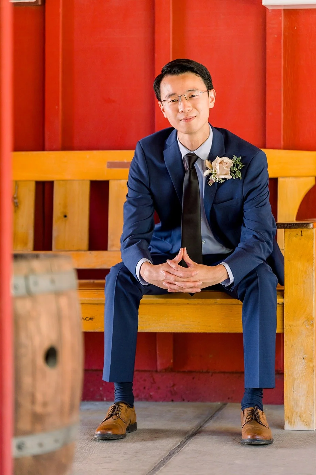 Alex seated on a bench in front of the red barn