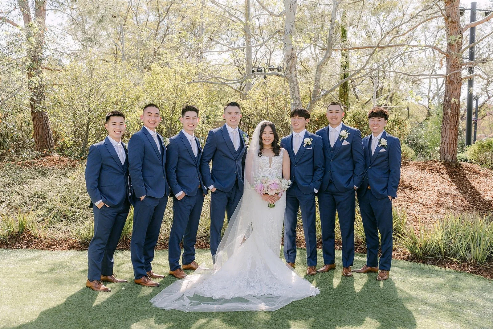 Kelli and Alex with the groomsmen in navy suits on the lawn at Los Robles Greens
