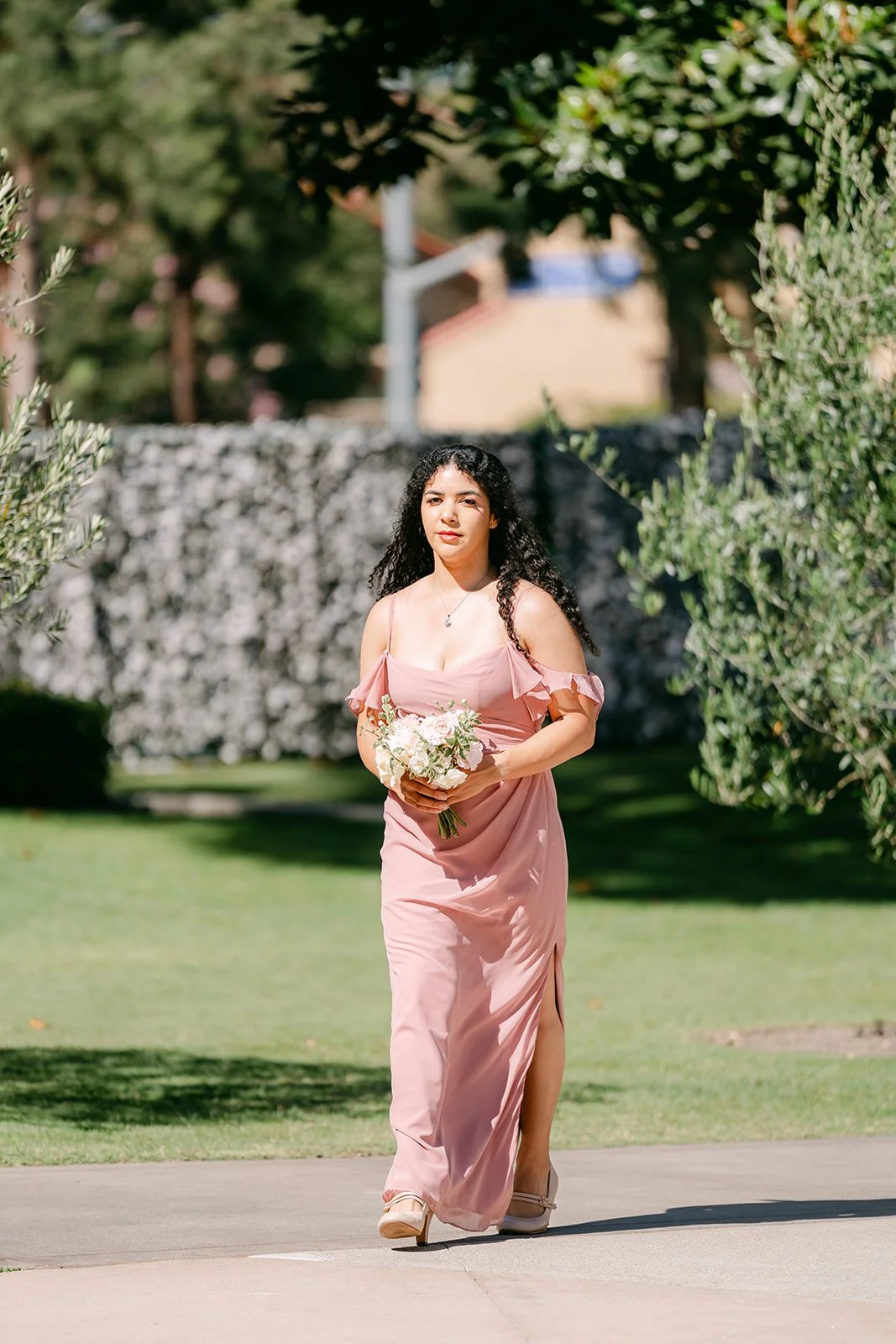 A bridesmaid in dusty pink walking down the aisle.