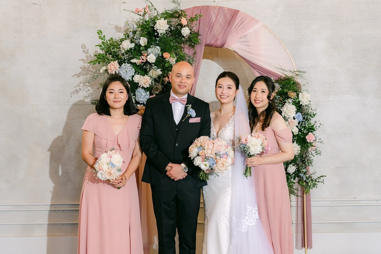 Elisa and Brandon with their bridesmaids at the floral arch