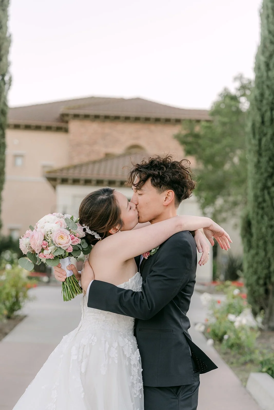 Groom lifting the bride for a kiss on the garden path