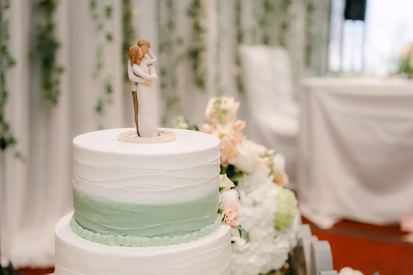 The sage green and white wedding cake with a carved couple topper
