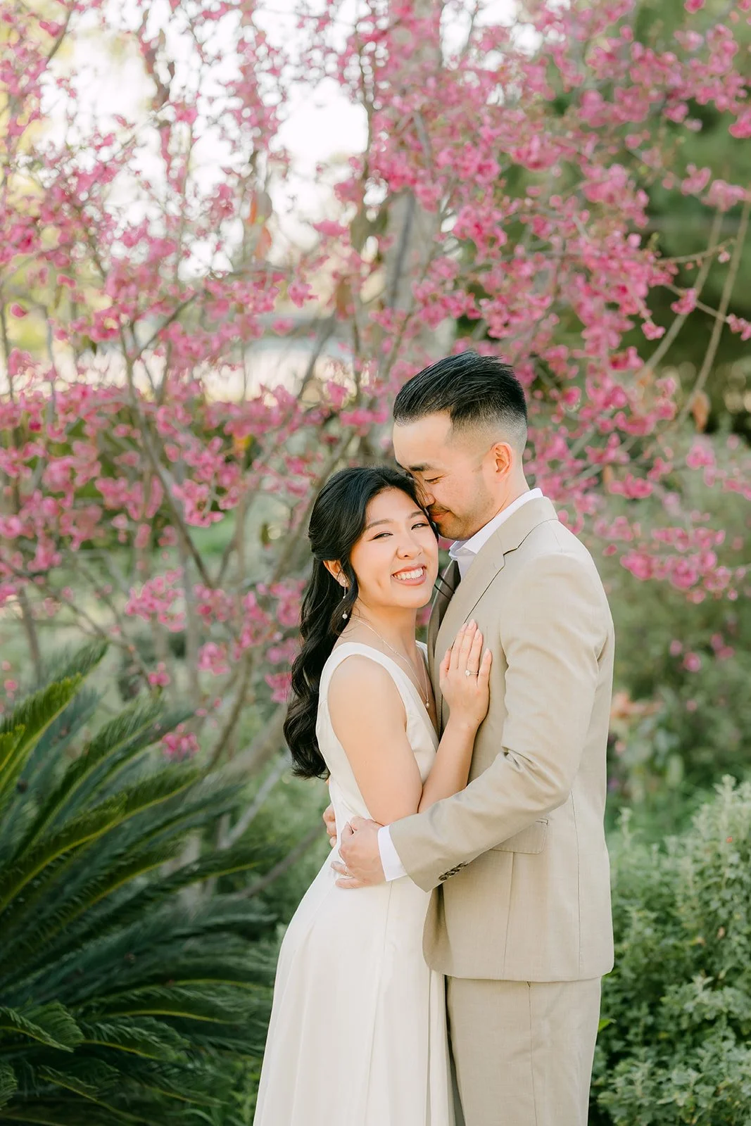 Kim leaning into Vincent under pink spring blossoms.