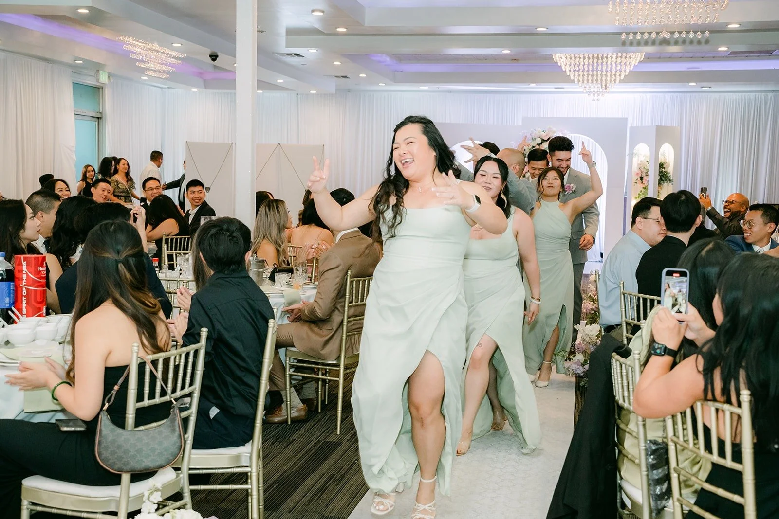 A bridesmaid in sage dances her way into the reception