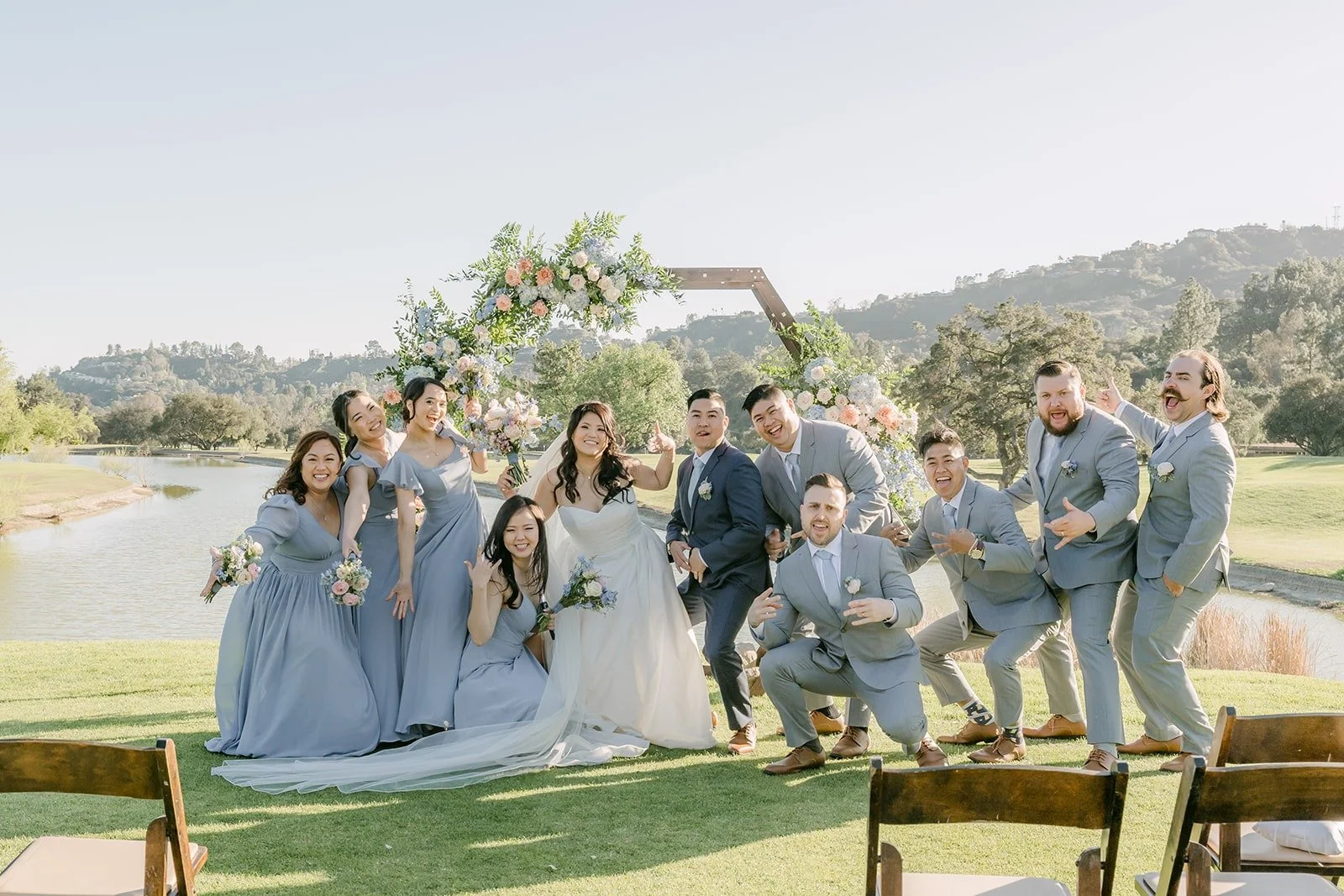 Bridesmaids in dusty blue posed in front of the ceremony arch