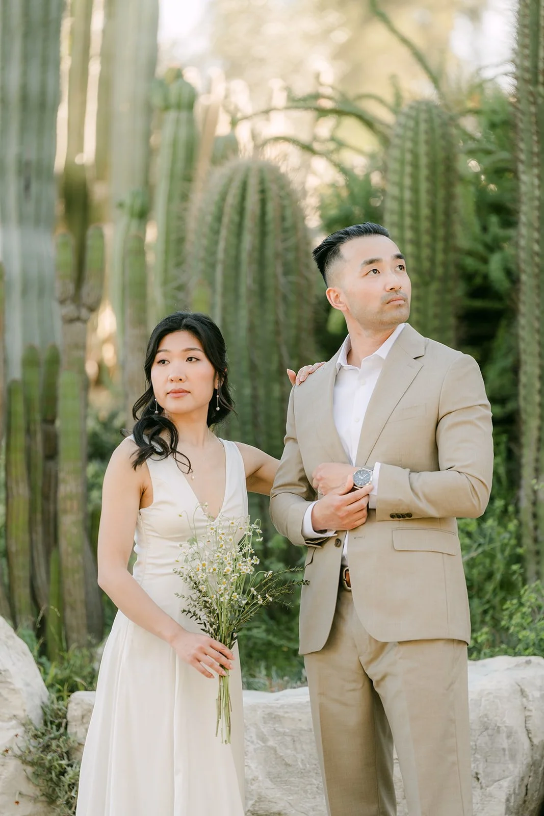 Kim and Vincent holding her bouquet together in front of the cacti.