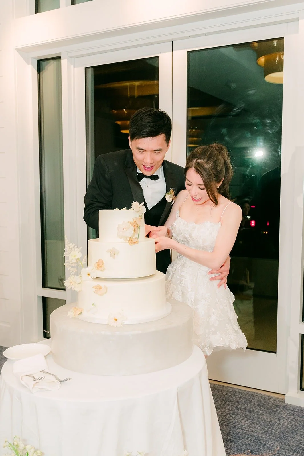 Angela and Eli slicing into the cake by the ballroom windows