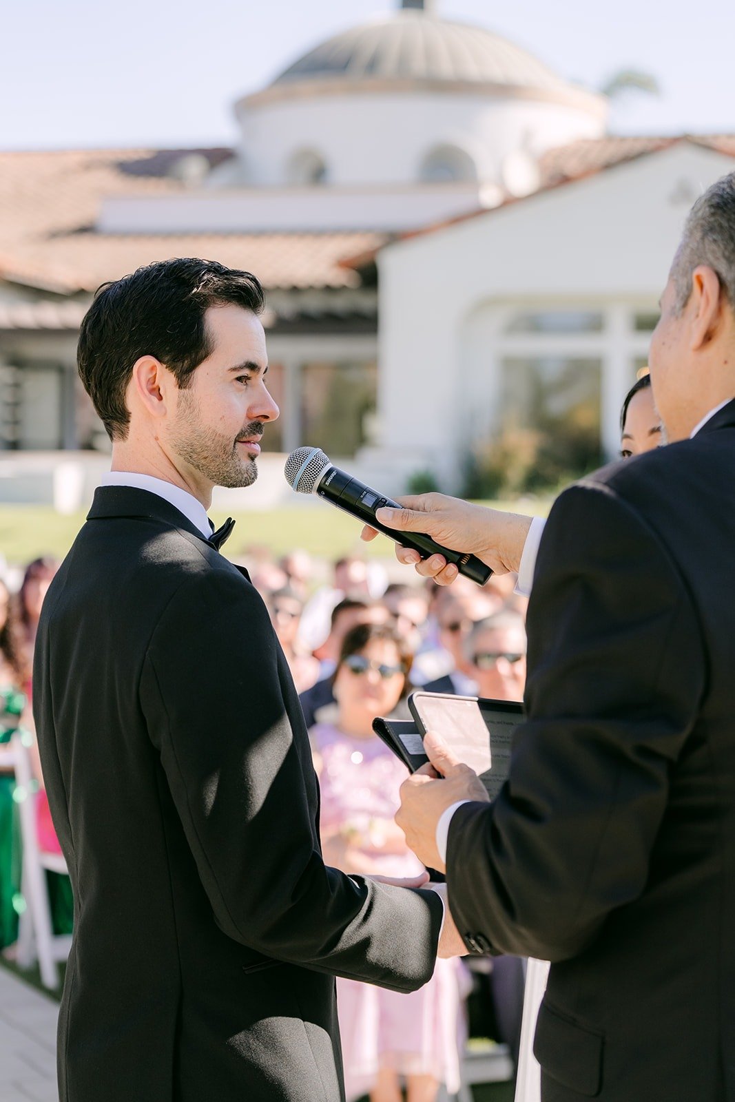 Kevin speaking his vows into a microphone with the clubhouse behind him