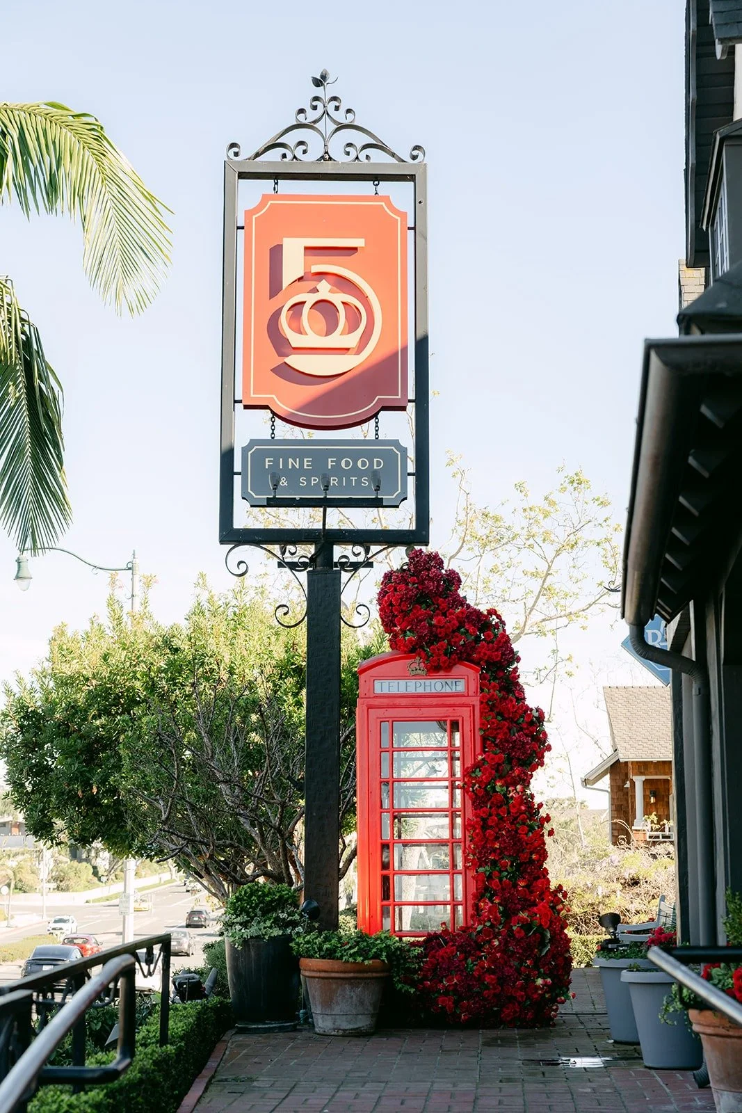 The Five Crowns sign above a red phone booth covered in red roses in Corona del Mar