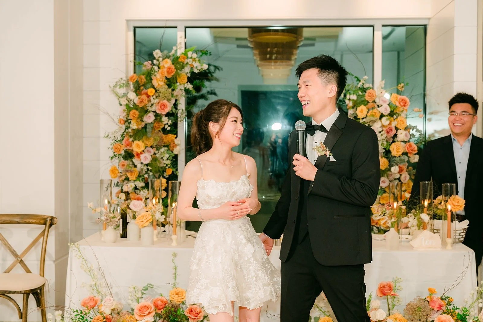 Angela and Eli standing together at the sweetheart table during the speeches