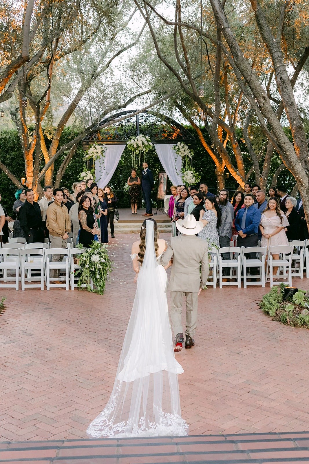 Mariana's veil trailing behind her on the aisle as guests stand