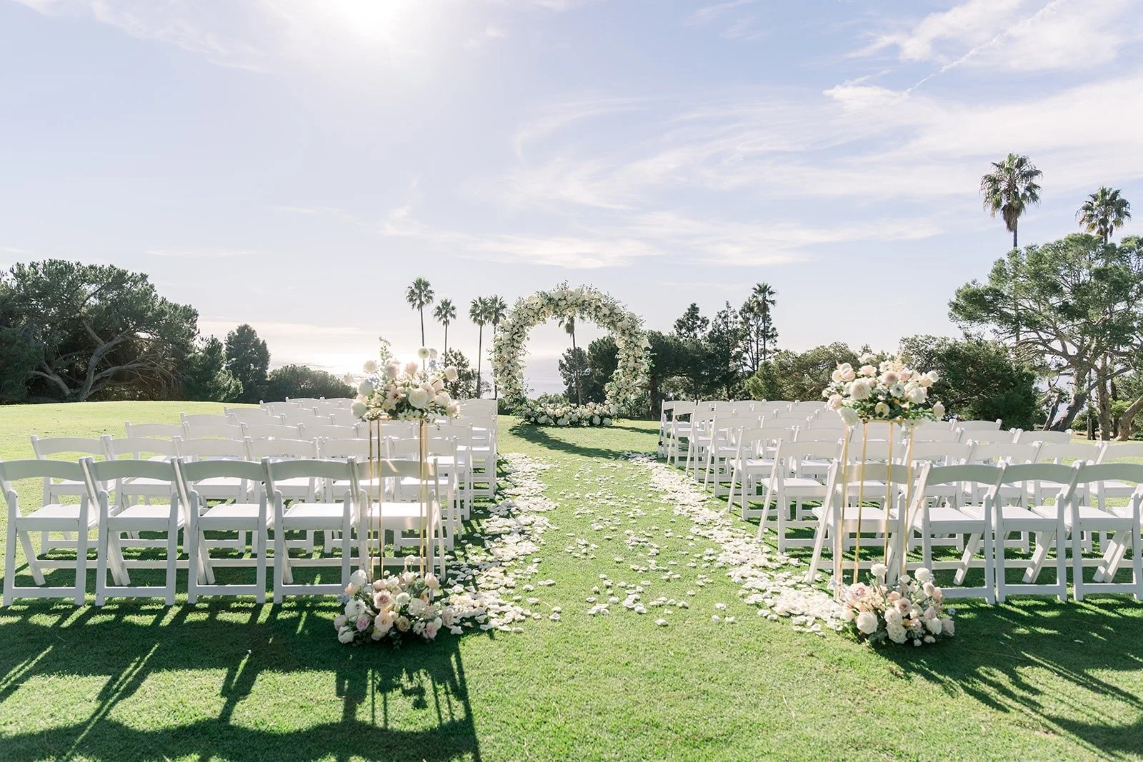 The ceremony lawn set with white chairs and a floral arch