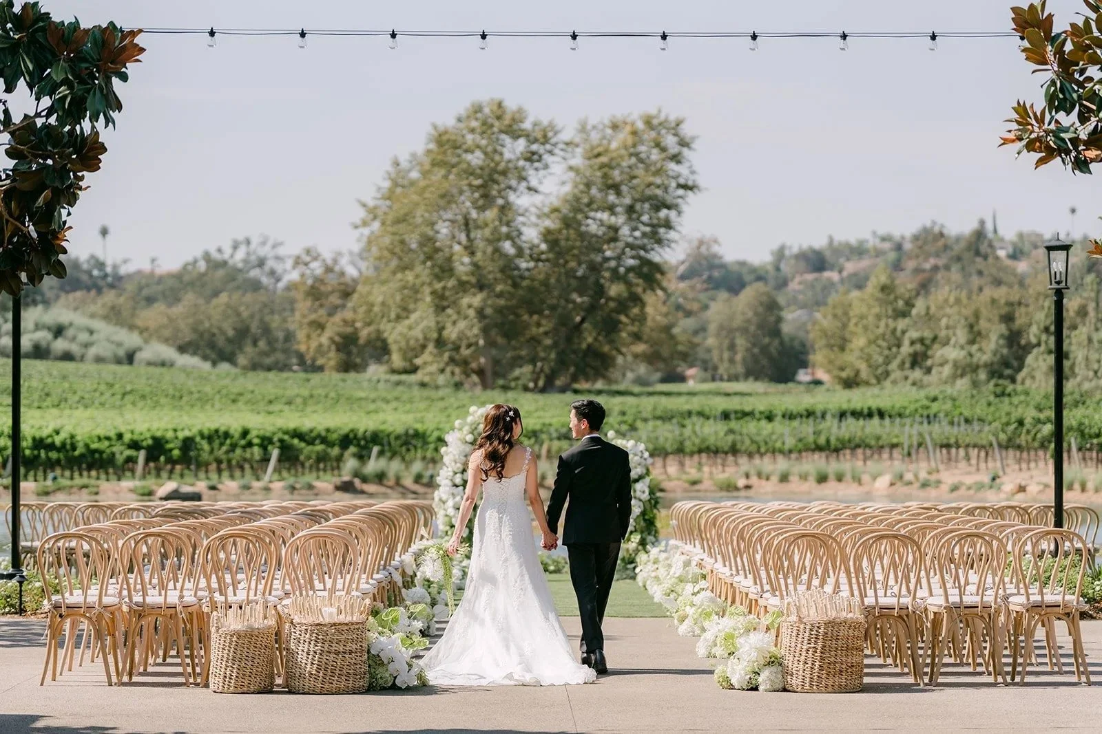 Marina and Tyler walking down the aisle toward the vineyard before guests arrive