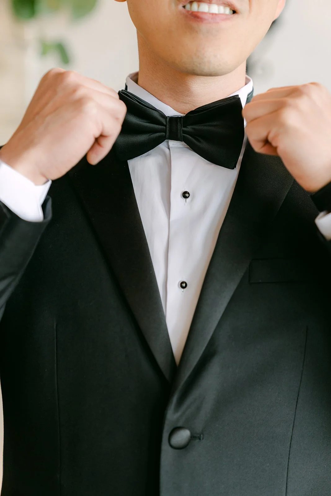 Close-up of the groom adjusting his black bow tie