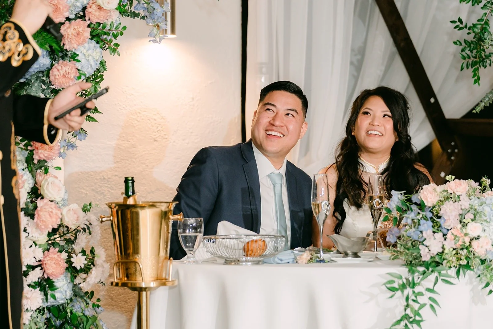Florence and Jordan laughing at the sweetheart table during speeches