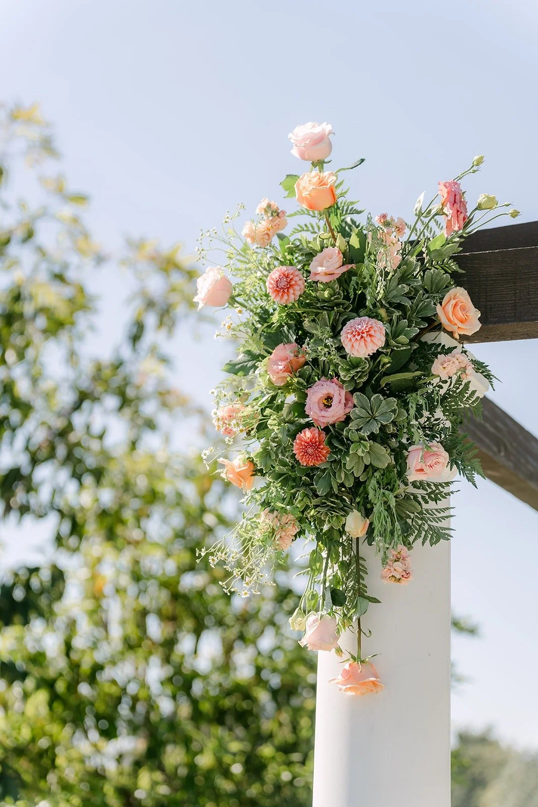 A close view of the ceremony florals on a white pagoda column, photographed by One and Only Production