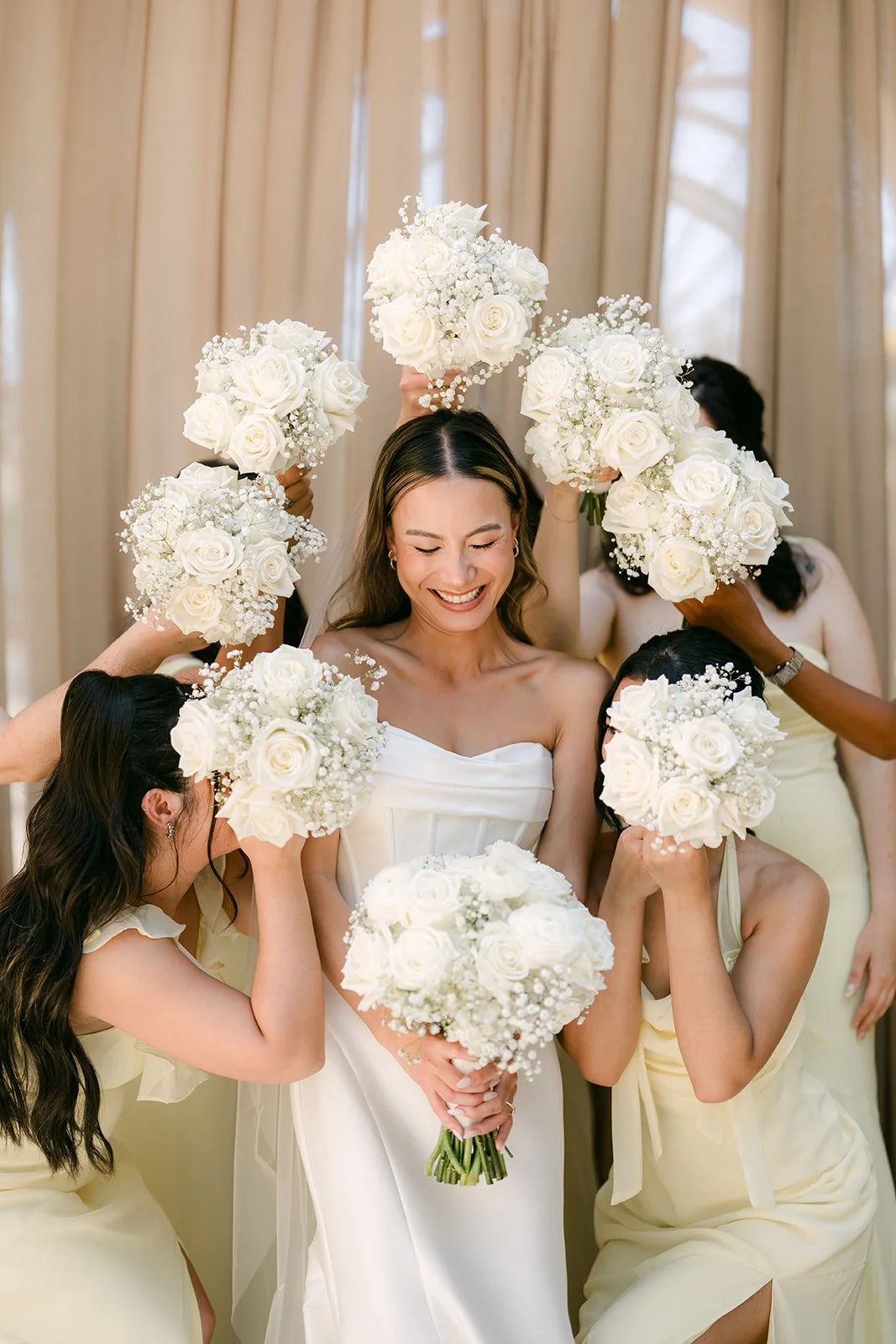 Bridesmaids holding white bouquets around the smiling bride
