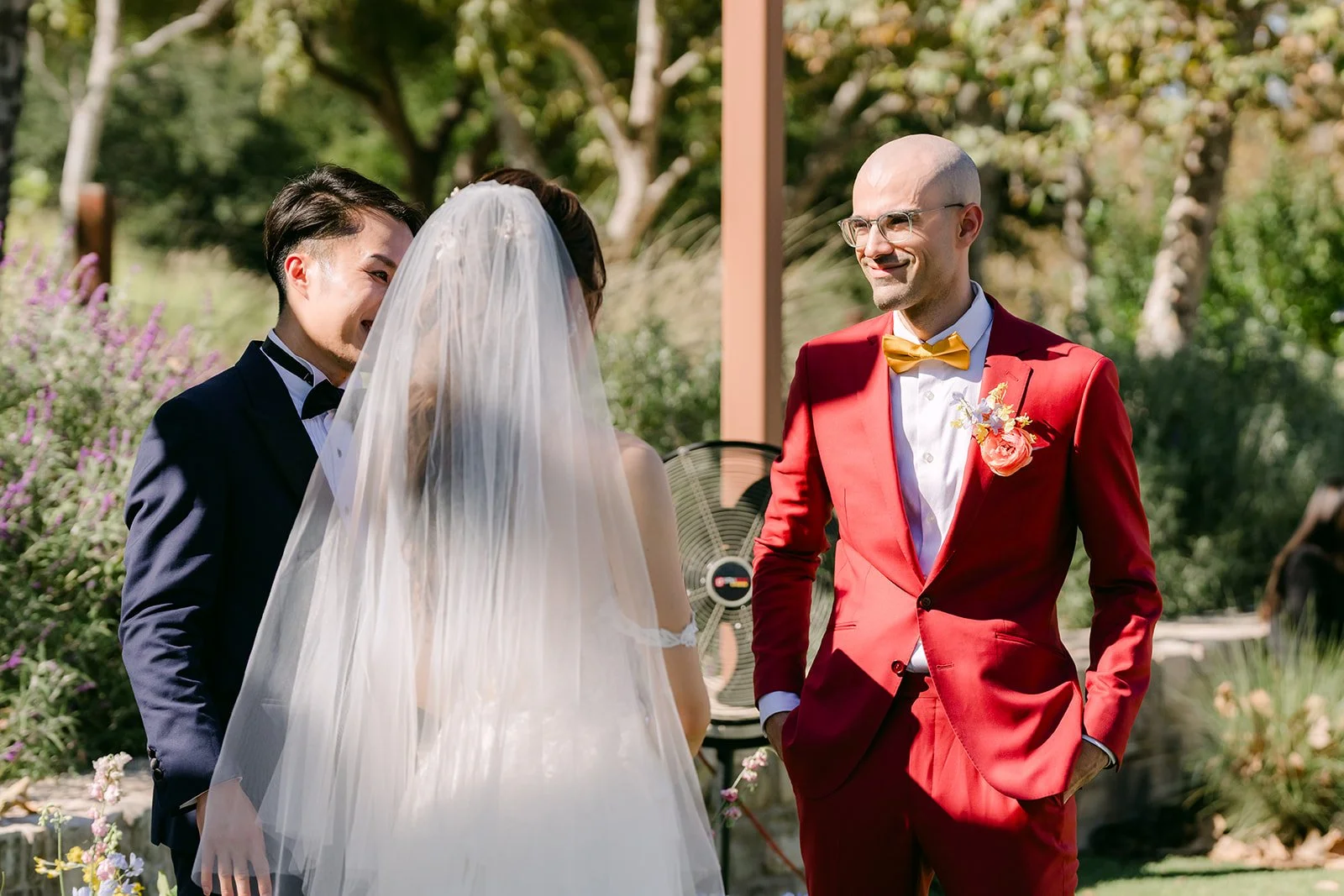 Christian smiling at Christie during the ceremony as her veil catches the light.