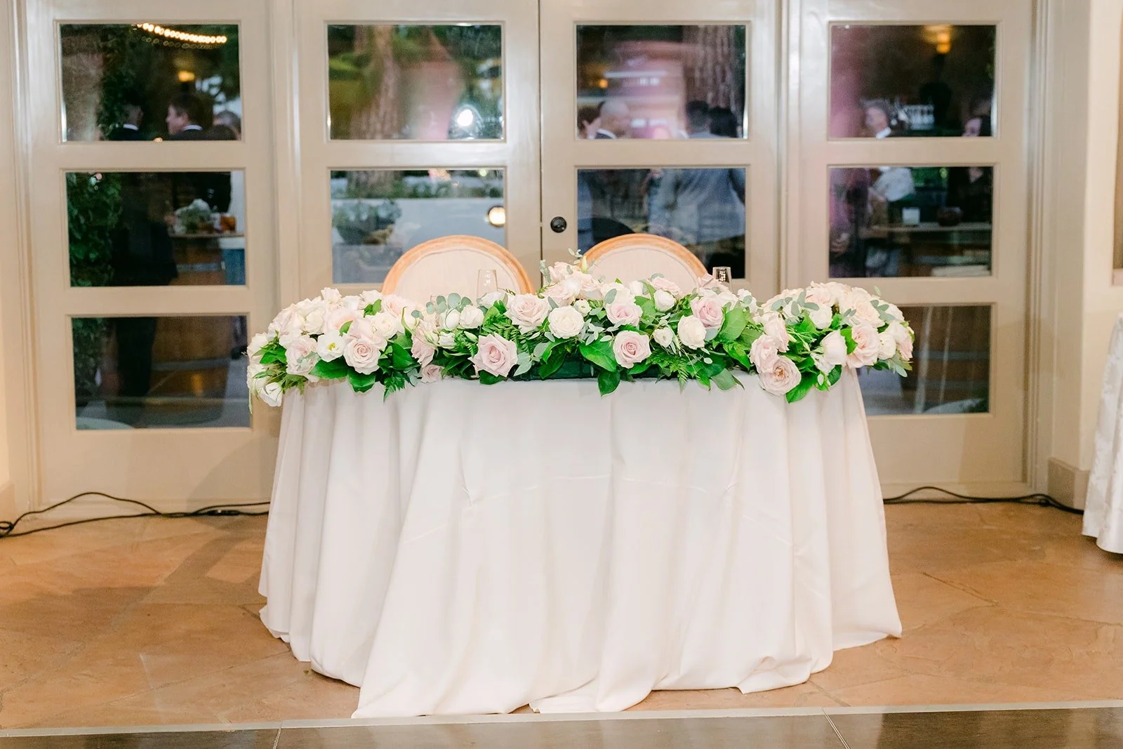 Head table lined with white florals by the windows