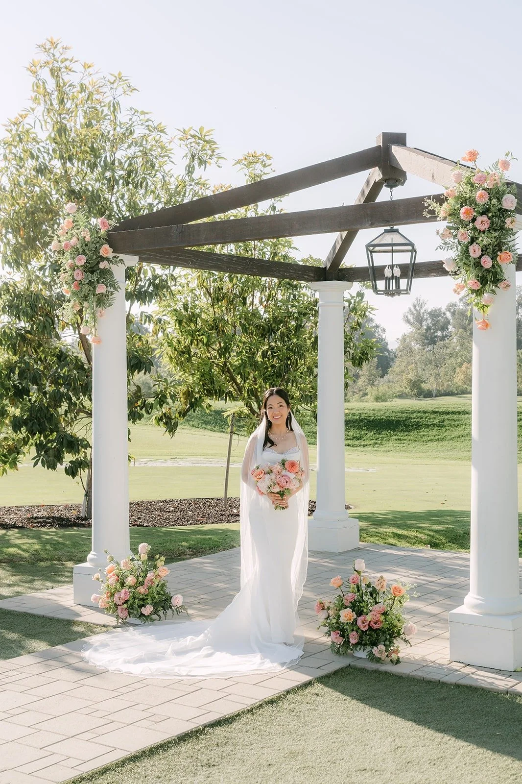 Stephanie standing under the wooden pagoda at Sterling Hills with her bouquet