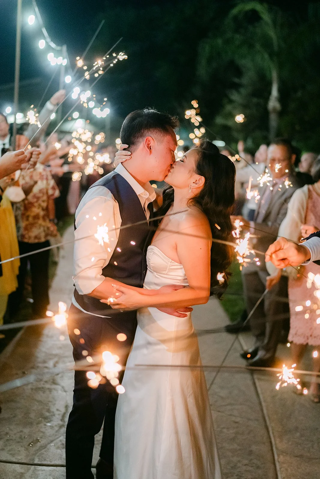 Vannie and Elijah kissing in a tunnel of sparklers.