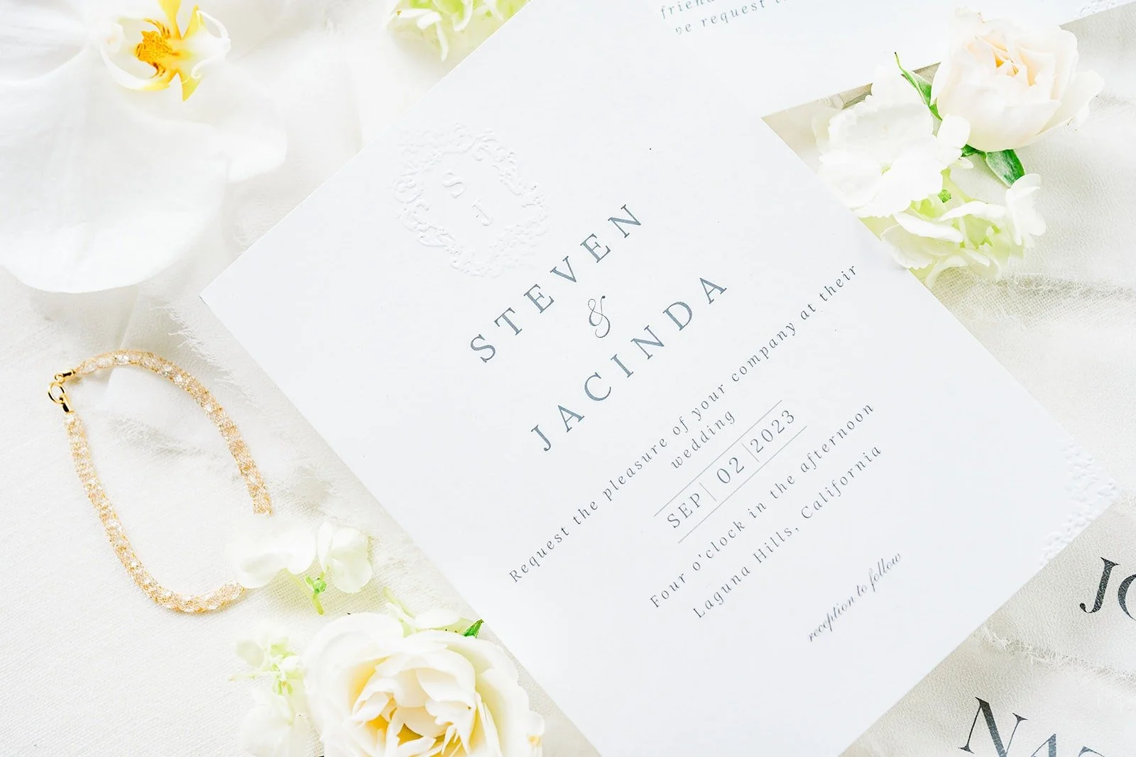 The wedding invitation styled with white orchids and gold accents
