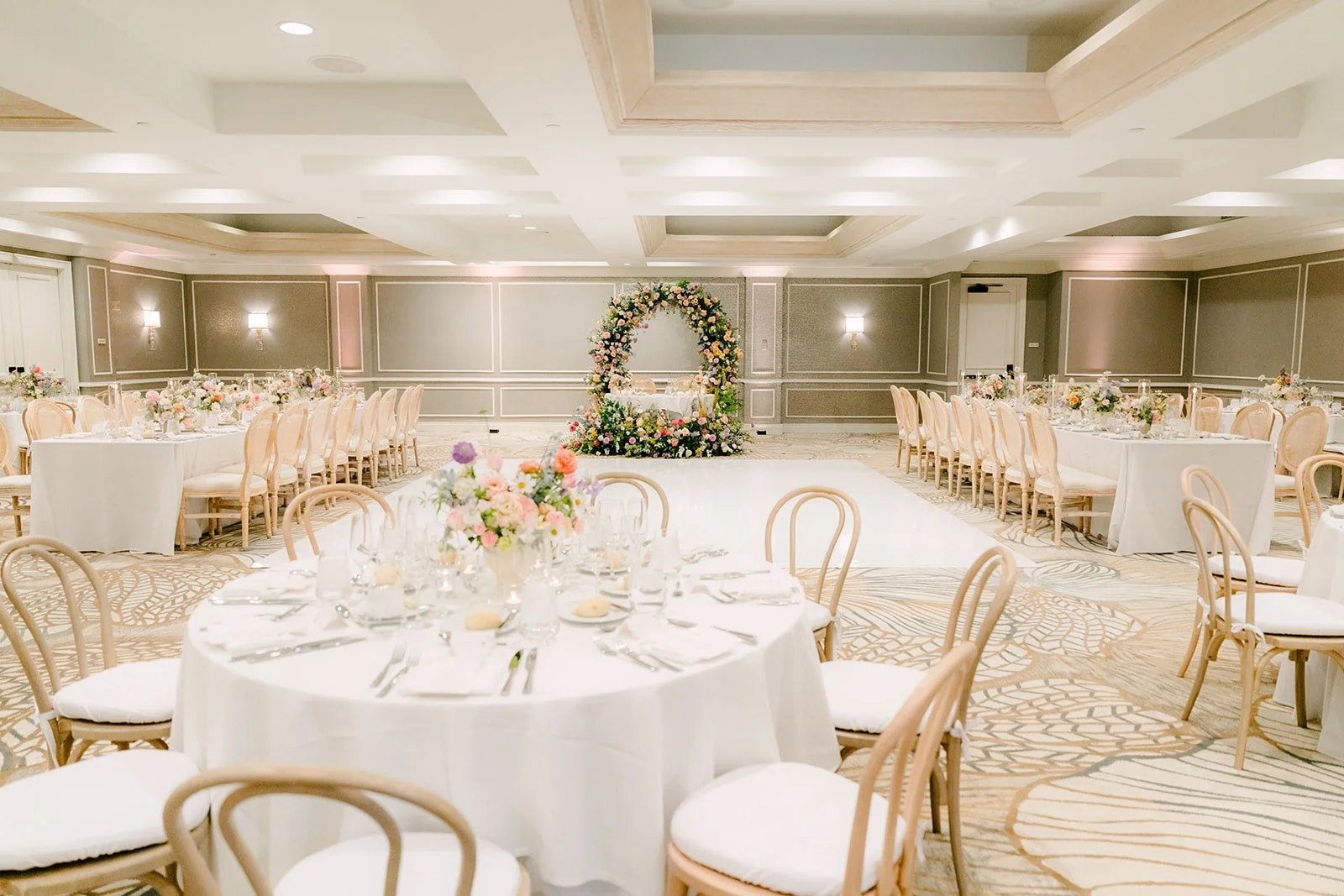 The ballroom set with round tables, cross back chairs and pastel centerpieces