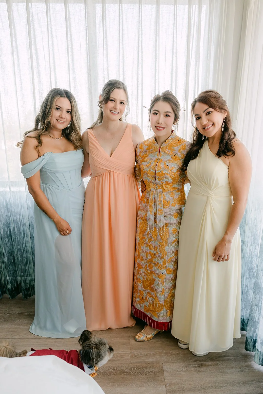 Christie laughing with her bridesmaids in sky blue, peach and lemon dresses.