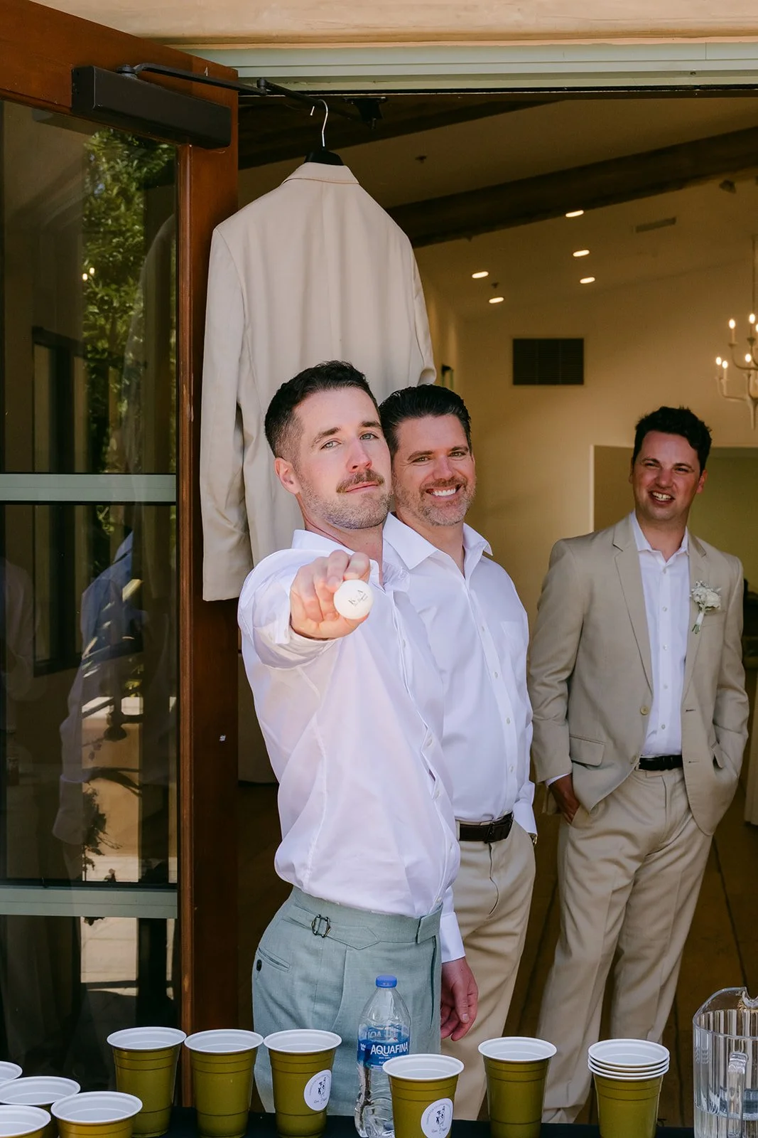 Groomsman tossing a ping pong ball during a game of beer pong before the ceremony
