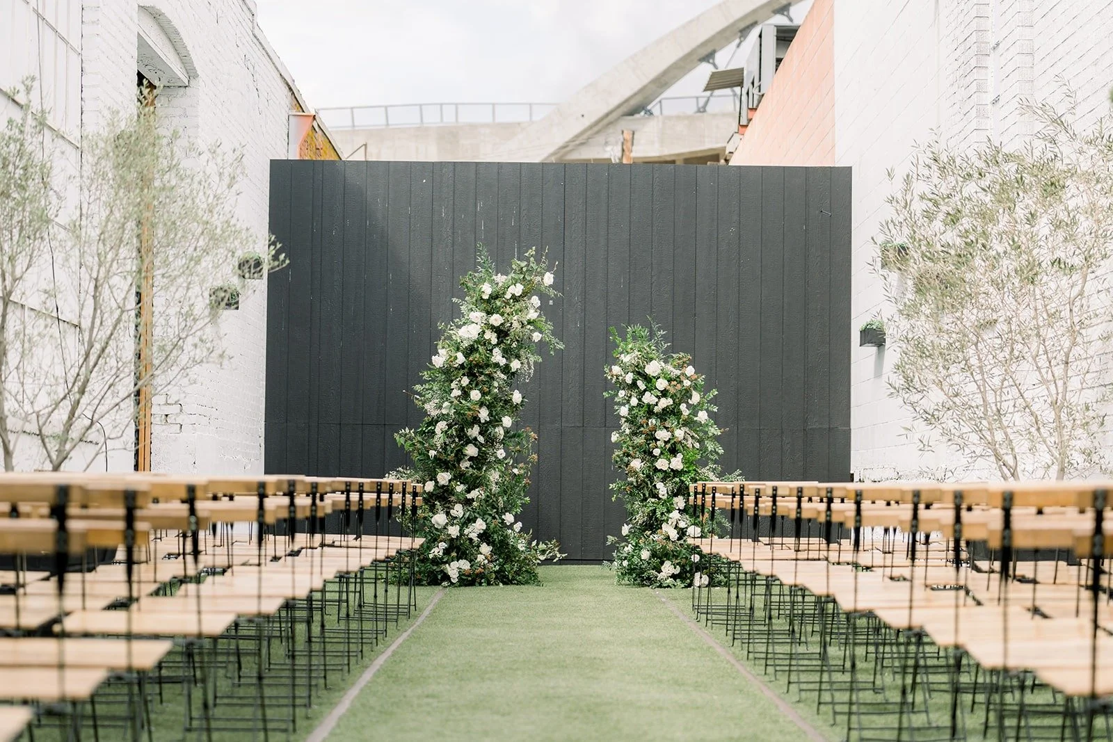 The ceremony aisle on the turf courtyard with white floral columns