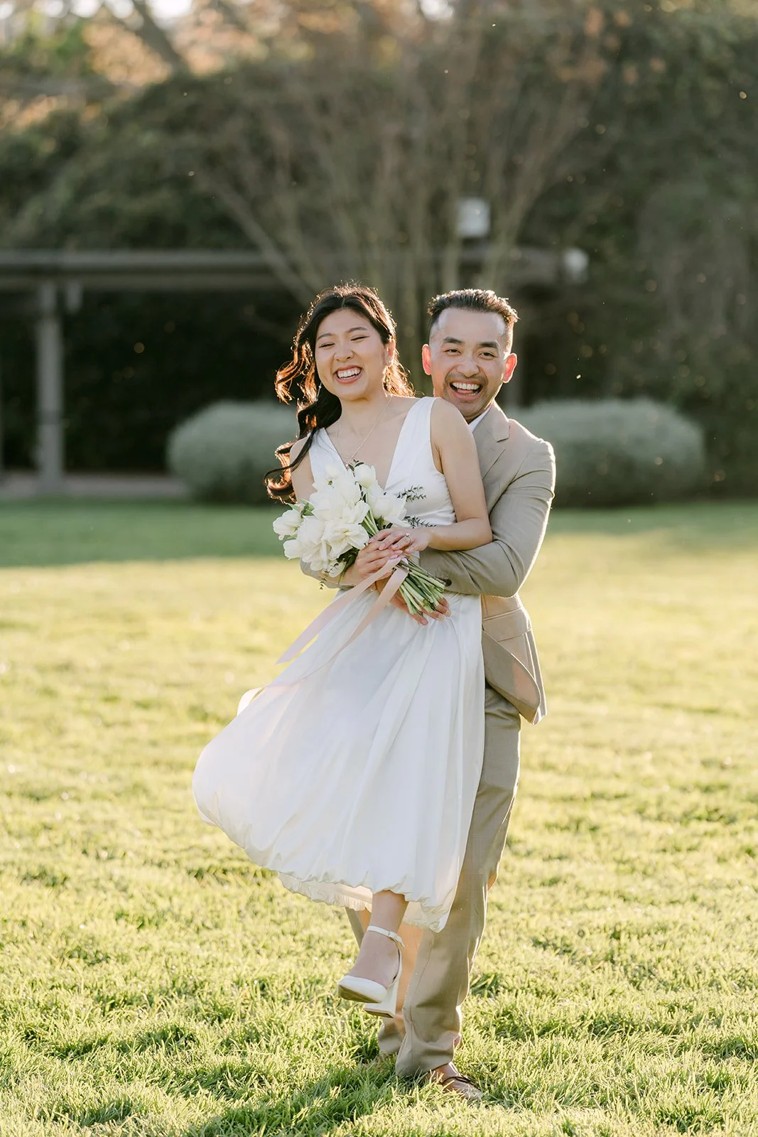 Kim laughing as Vincent holds her on the grass.