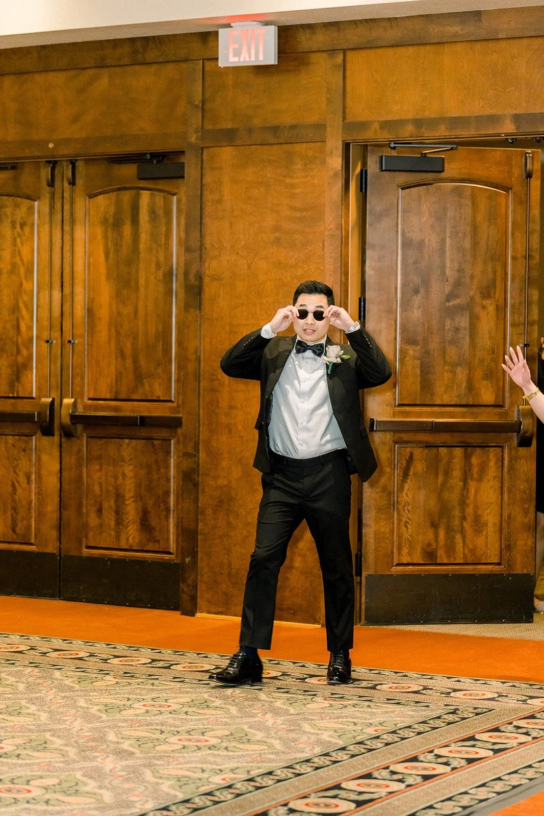 A groomsman in sunglasses striking a pose through the doors