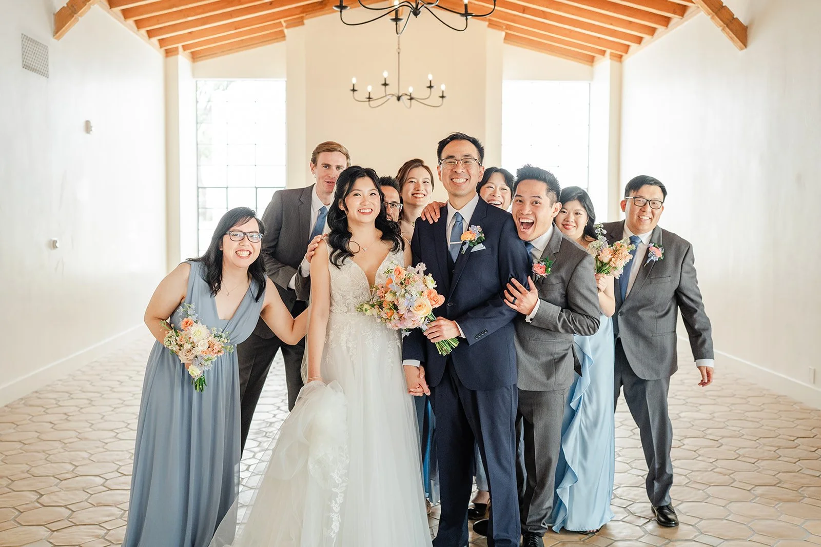 Wedding party huddled together laughing, photographed by One and Only Production