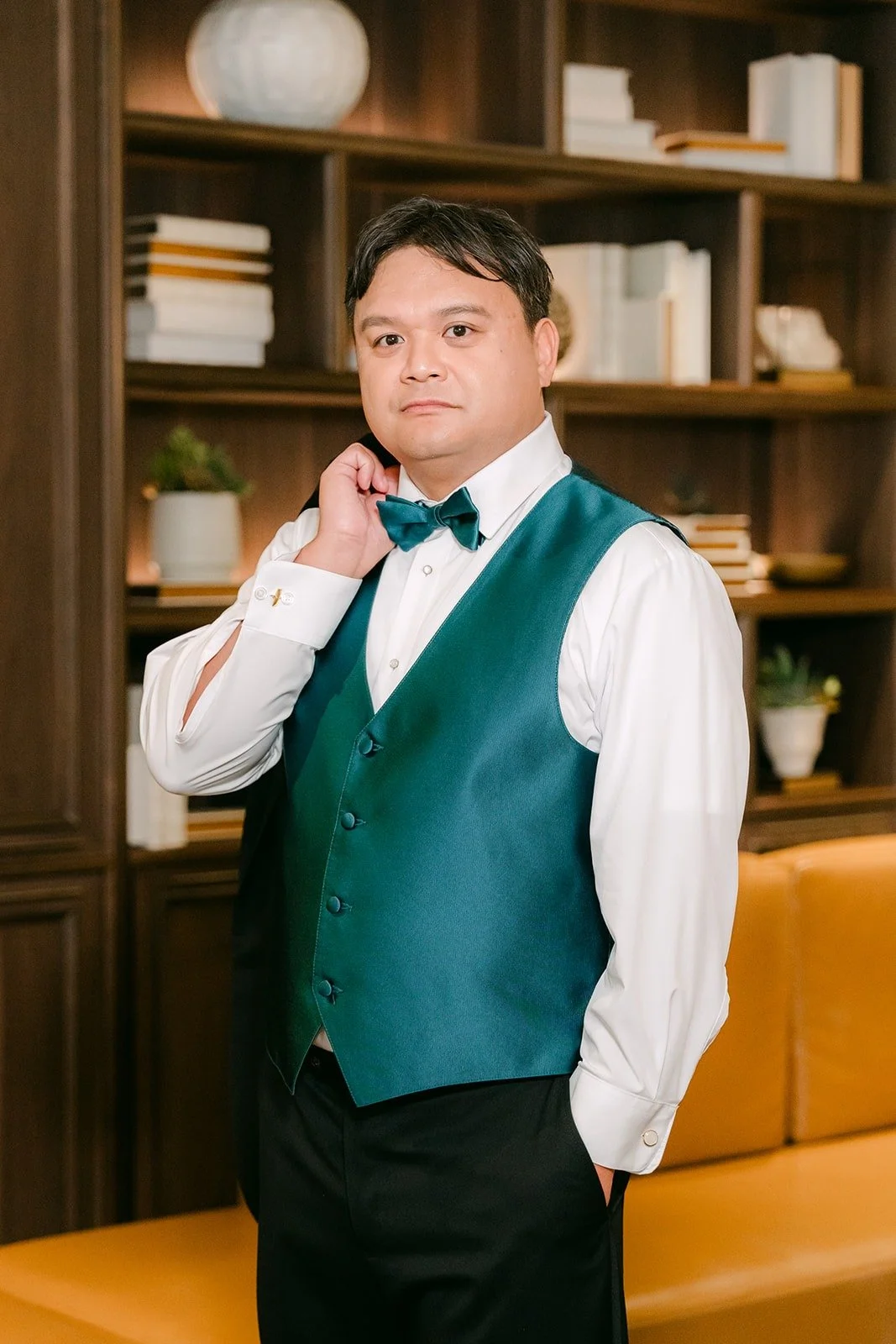 James in his white shirt, teal vest and bow tie, smiling at the camera